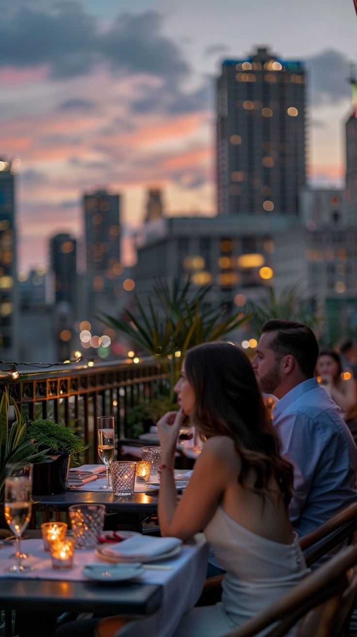 A couple enjoying a romantic dinner on an upscale rooftop restaurant with a city skyline view at sunset