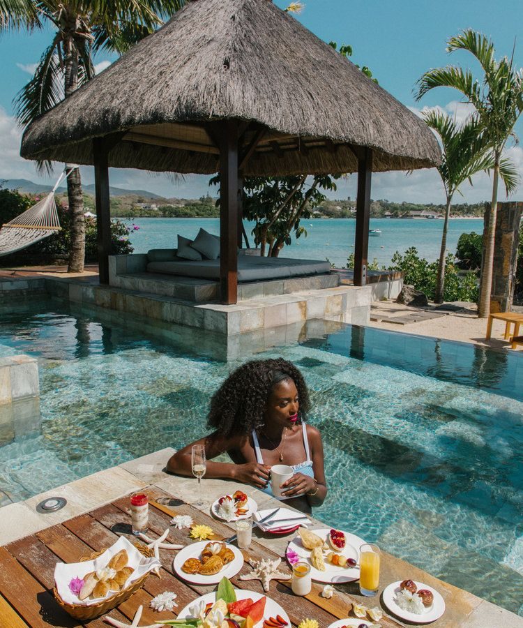 An image of a lady enjoying a luxurious floating breakfast experience by the pool - The Curated Table
