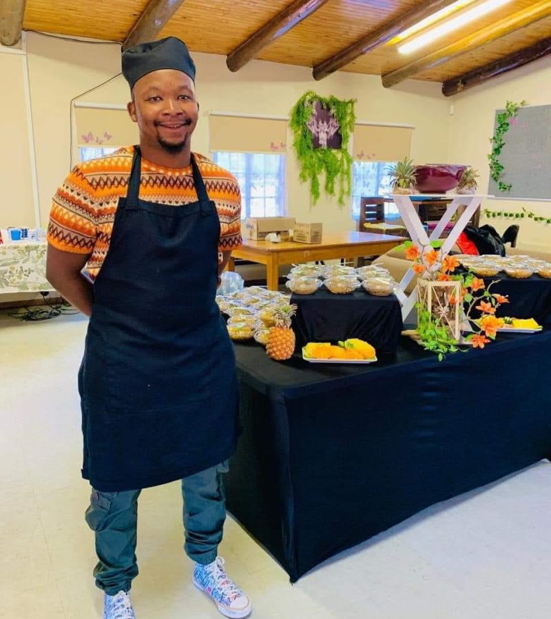 Image shows a catering event setup with a chef standing next to a food buffet table - The Curated Table