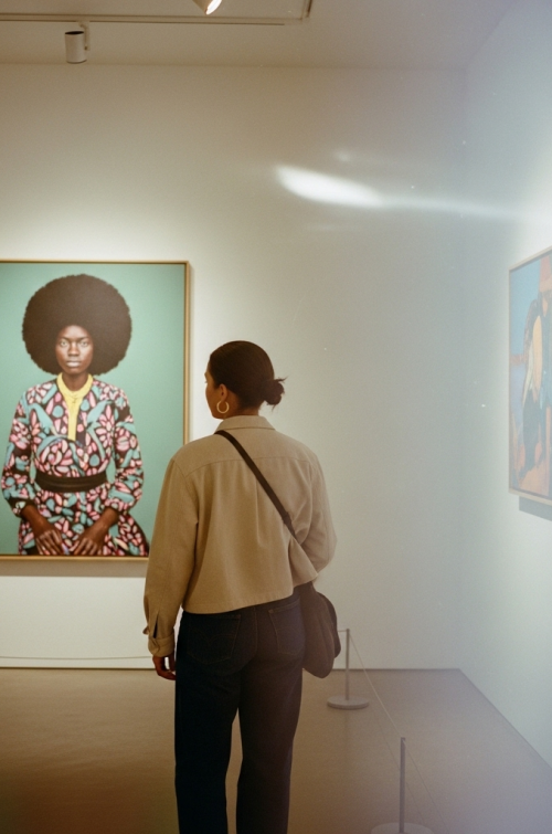 image captures a moment in an art gallery, likely at an exhibition featuring contemporary Black artists